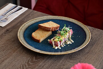Served veal tartare with toasted bread in a modern style, elegantly plated in a restaurant setting. Close-up of the dish on the table, highlighting the texture of the meat and sophisticated presentati