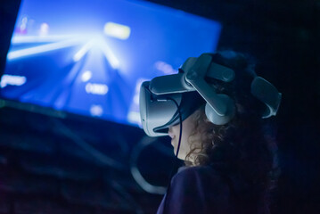 VR Gamer in a dimly lit room, intensely engaged in a virtual world