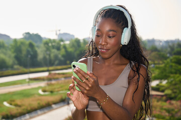 Young woman wearing headphones using smartphone in a city park