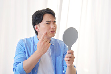 鏡を見る男性　20代　肌トラブル
