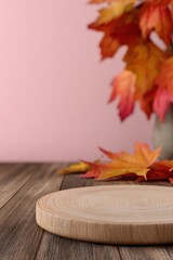 Wooden podium displaying fall colors with autumn leaves on a pink background, ideal for showcasing products