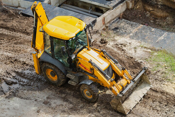  Yellow excavator stands on construction site, excavator ready for construction work, urban construction and landscaping with heavy machinery.