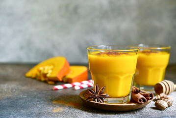 Spicy autumn pumpkin smoothie with cinnamon and honey in a glasses .