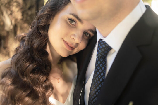 Closeup of happy couple having photoshoot outdoors, hugging. Young groom and bride getting married, smiling, enjoying, having photoshoot. Concept of happiness and family relations.