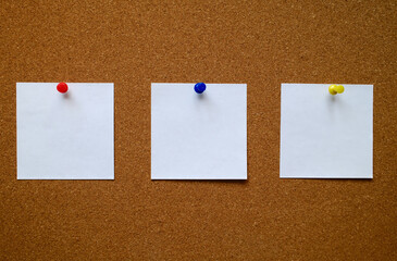 Three white blank notes pinned to a cork message board