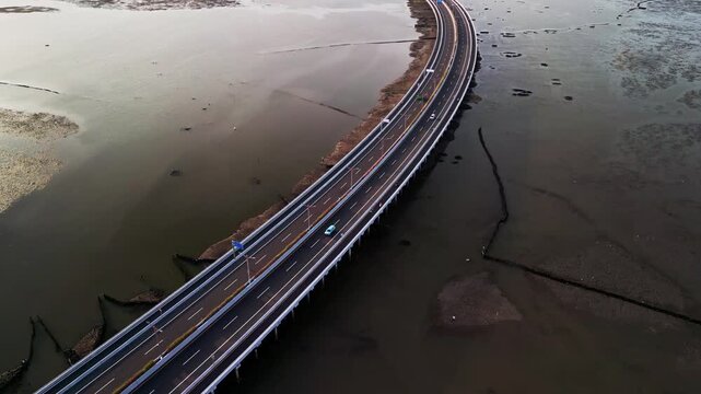 Bali Mandara Toll road bridge is filmed from drone flying high over tidal mud at low tide the tropical coastal view combines natural mudflats with modern island connection highway
