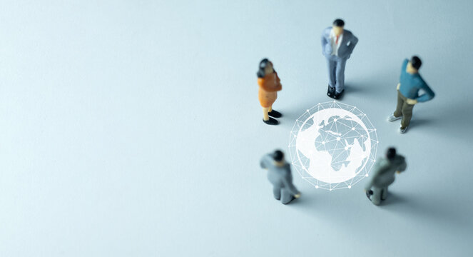 Miniature business people in a meeting around a virtual globe network. A concept for global business, international strategy, globalization, worldwide teamwork, and corporate management.