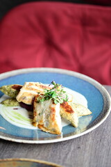 Grilled fish fillet with white sauce and herbs on a plate