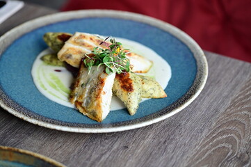 Grilled fish fillet with white sauce and herbs on a plate
