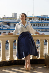 A girl stands with a suitcase in her hands on the embankment of the river station, port.