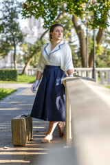 A girl stands with a suitcase in her hands on the embankment of the river station, port.