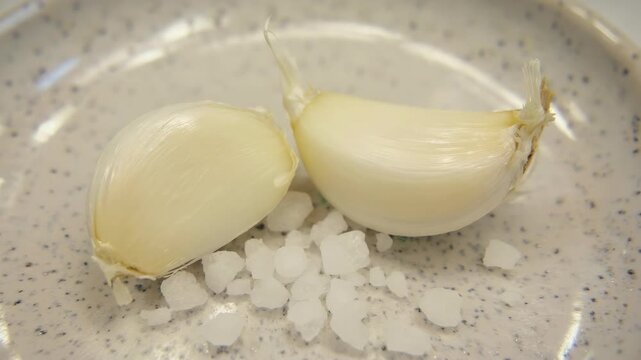 Close-up of garlic bulbs on a plate with salt beside them.
