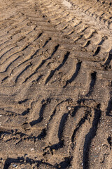 car tracks on the soil in the field, deep tracks from a very heavy vehicles in the field after harvesting