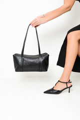 Young woman in elegant high heel shoes holding black leather bag