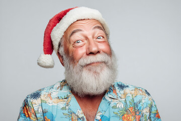 happy bearded elderly man in a floral Hawaii shirt and Santa hat, neutral studio background