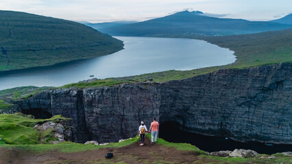Visitors admire the stunning cliffs and serene waters of a fjord in the Faroe Islands during the...