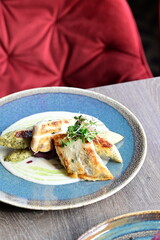 Grilled fish fillet with white sauce and herbs on a plate