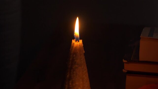 Candle flame flickers gently in a dimly lit room, illuminating surrounding objects, creating a warm autumn ambiance and cozy atmosphere. autumn is coming concept 