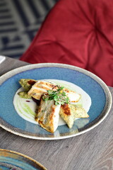 Grilled fish fillet with white sauce and herbs on a plate