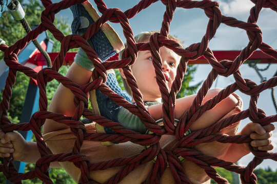 Happy boy swings on a rope nest swing - Powered by Adobe