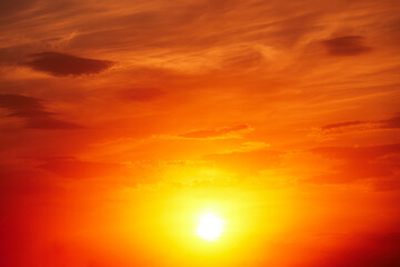 Obraz premium Beautiful colorful dramatic sky with clouds at sunset. Bright orange setting sun low on the horizon. Cirrus clouds change color from blue to yellow to red. Stunning backdrop, gorgeous scenery.