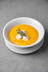 Creamy pumpkin soup with feta cheese and thyme garnish
