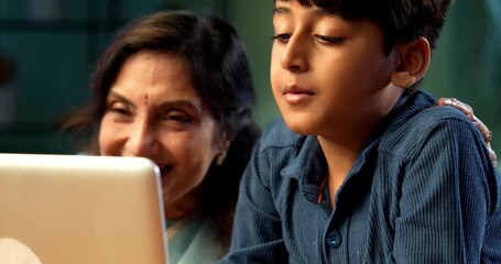 Indian grandmother with kid using laptop computer at table in modern home indoors, elderly woman learning technology from child, family bonding across generations, digital education, love and care - Powered by Adobe