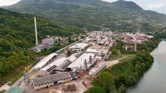 industrial zone of Brod Foča Zubovići in Bosnia and Herzegovina moving over industrial buildings with green forest surrounding the area and a river on the right