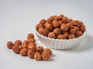Raw hazelnuts without shells in a bowl on a white background

