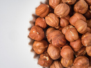Raw hazelnuts without shells in a bowl on a white background
