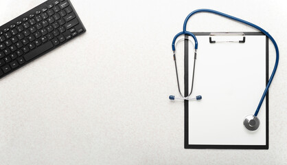 Medical background of stethoscope clipboard and computer keyboard flat lay on table with copy-space