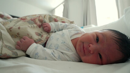 Newborn baby resting under a floral blanket, grimacing and gesturing as they explore their surroundings, the first month of life and early developmental milestones-SD 480p