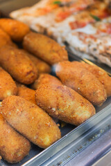 Crocchè di patate appena fritti e pronti per essere venduti in una vetrina da vendita di una pizzeria