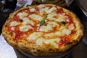 Pizza Margherita tradizionale napoletana con sugo di pomodoro, mozzarella di bufala e basilico fresco appena sfornata in una pizzeria