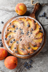 Blueberry Peach Sour Cream Cake with fresh summer fruit closeup on the wooden board on the table. Vertical top view from above