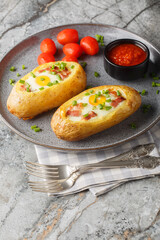 Twice baked potatoes with bacon and egg close-up in a plate on the table. vertical