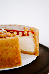 Delicious cheesecake with caramel topping served on a black platter in a bright kitchen