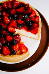 Delicious fruit-topped cheesecake served on a brown plate in a bright kitchen setting