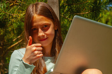Beautiful teenager enjoys distance learning in harmony with nature. Horizontal image.