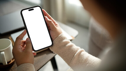 Close up of woman holding smartphone with blank white screen at home.