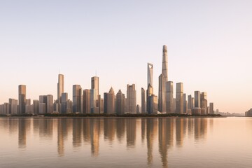 Fototapeta premium Modern Cityscape Reflection at Sunset: Urban Skyline of Skyscrapers Along Calm River in Downtown