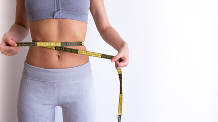 Front-facing image of woman measuring waist with tape . Lifestyle and weight-management concept for fitness and diet articles. 
