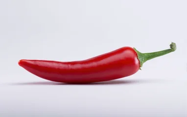 Küchenrückwand glas motiv Scharfe Chili-pfeffer A short red chili pepper is seen from the side, showcasing its bright hue and elongated shape against a neutral background  © Jam
