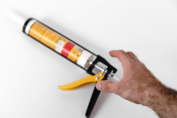 Hand preparing to use a caulking gun for home repair project in a well-lit workspace