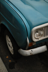 Close-up of old blue classic car showing headlight, bumper and fender details