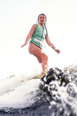 Fototapeta premium Young woman wakeboarding on a lake during a sunny day
