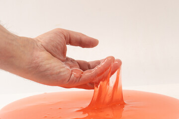 Red slime toy in man hand isolated on white.