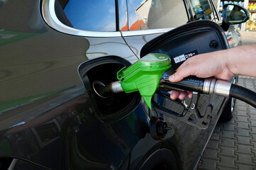Hand refilling a car with fuel at a gas station, closeup © Alina Yermakova