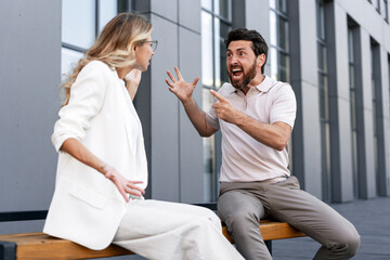 Businessman yelling at businesswoman sitting on bench during break
