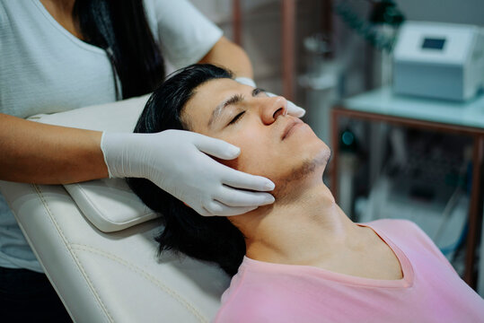 Male client receiving a facial massage as the therapist gently works along his jawline in a spa or aesthetic clinic.